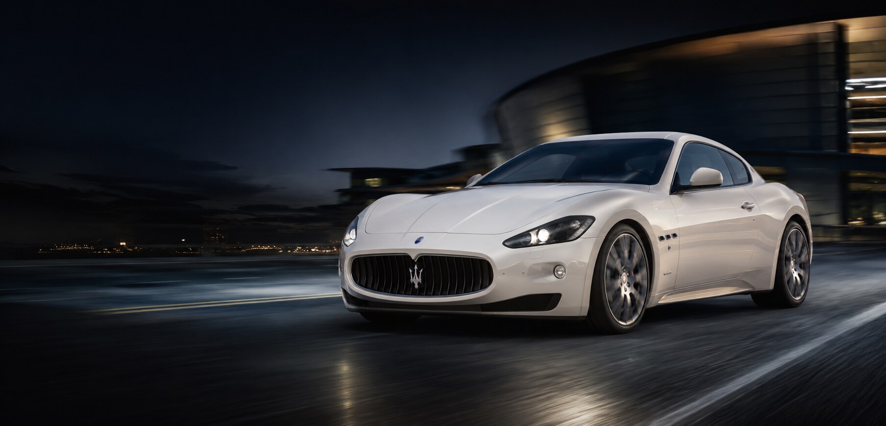 Pearlescent white 2012 Maserati GranTurismo in Bianco Fuji accelerating on a dark road